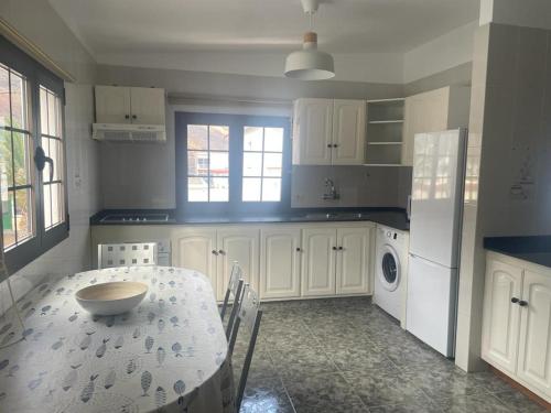 uma cozinha com uma mesa e uma cozinha com armários brancos em APARTAMENTO ROSALIA em Timijiraque
