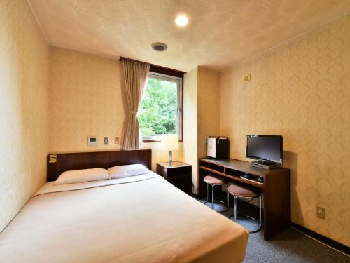 a bedroom with a bed and a desk with a television at Hotel Kangetsuso in Tokyo