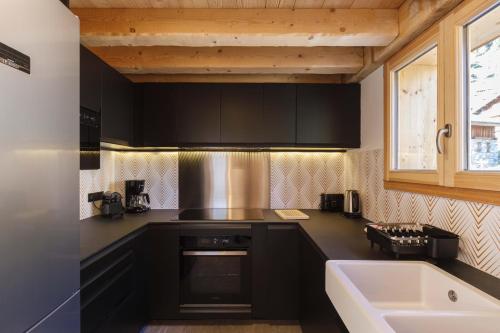 cocina con armarios negros, fregadero y bañera en Bio Corti Spa 12 personnes, en Champagny-en-Vanoise