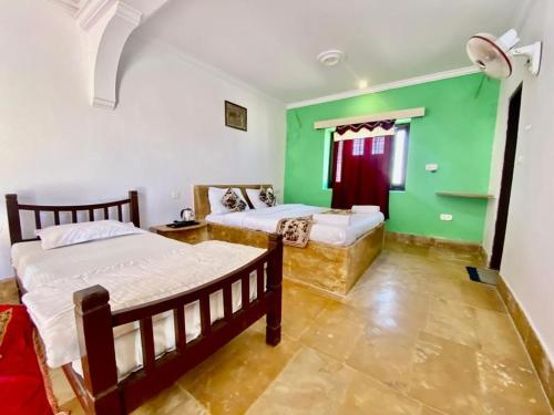a bedroom with two beds and green walls at Mariyan Desert Safari Camp in Sām