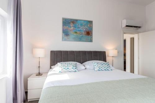 een witte slaapkamer met een groot bed met 2 kussens bij Villa Sky in Primošten