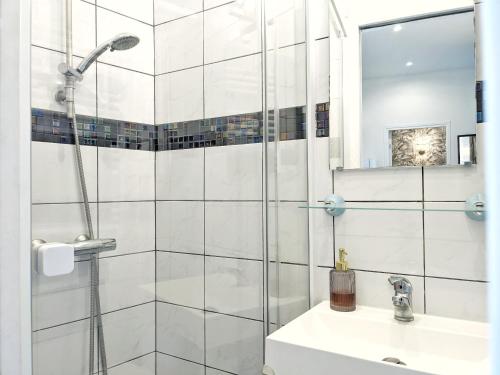 uma casa de banho branca com um chuveiro e um lavatório. em Appartement Ardoines Shelter em Vitry-sur-Seine