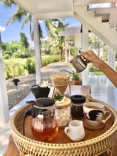 una persona vertiendo café en una mesa en un patio en Huen Chaivaree, en Nan