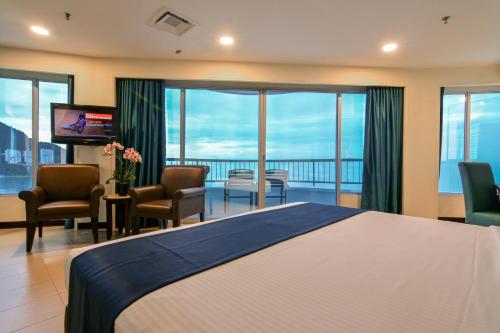 Habitación de hotel con cama grande y balcón. en Flamingo Hotel by the Beach, Penang, en George Town