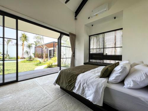 una camera con un grande letto e ampie finestre di KAKAO Villas Kedungu a Tanah Lot