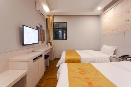 a hotel room with two beds and a flat screen tv at Qi Cheng Hotel - Shenzhen North Railway Station in Shenzhen