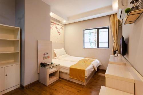 a small bedroom with a bed and a window at Qi Cheng Hotel - Shenzhen North Railway Station in Shenzhen
