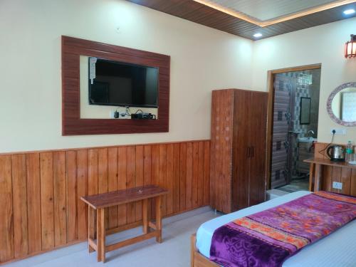 1 dormitorio con 1 cama y TV en la pared en Kaafal hotel & restaurant, en Dhanaulti