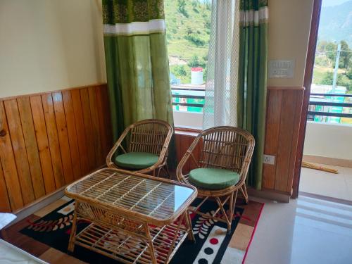 Habitación con 2 sillas, mesa y ventana en Kaafal hotel & restaurant, en Dhanaulti