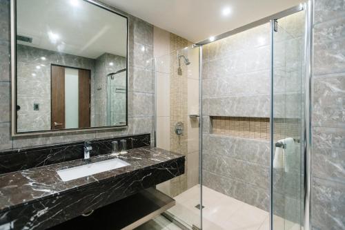 a bathroom with a sink and a glass shower at Zuri Hotel in Iloilo City