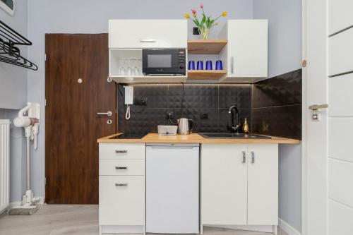 a kitchen with white cabinets and a sink and a microwave at Modern Studio Radomska by Renters in Krakow