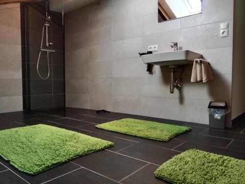 a bathroom with two green rugs and a sink at Ferienhaus Haueis in Tumpen