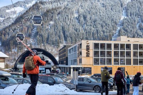 a person with skis on his back walking in the snow at Revier Mountain Lodge Montafon in Sankt Gallenkirch