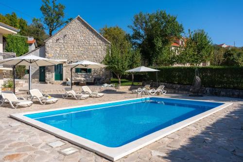 a swimming pool in a yard with chairs and umbrellas at Hacienda Sylvia - secluded 4-bedroom villa with 45sqm heated pool in Studenci