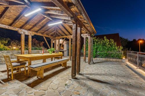 a wooden pergola with a wooden table and benches at Hacienda Sylvia - secluded 4-bedroom villa with 45sqm heated pool in Studenci