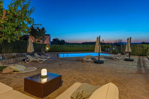 a swimming pool with umbrellas and chairs in a yard at Hacienda Sylvia - secluded 4-bedroom villa with 45sqm heated pool in Studenci