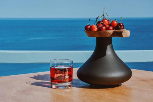 a glass of water and a vase with a bowl of apples at Chrysalis Boutique - Adults Only in Astypalaia Town