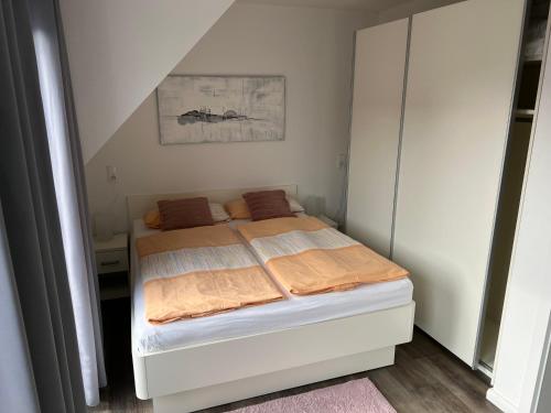 ein kleines Schlafzimmer mit einem Bett mit orangefarbener Bettwäsche in der Unterkunft Fewo Durak in Norderney