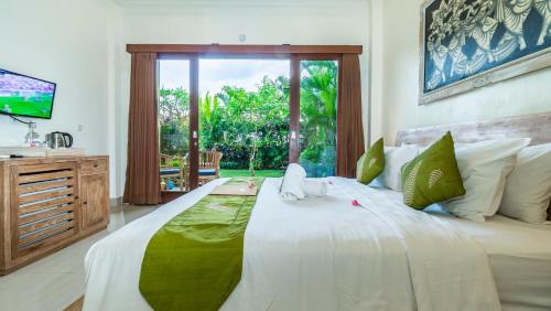 Schlafzimmer mit einem großen weißen Bett und einem Fenster in der Unterkunft Jegeg Mas in Ubud