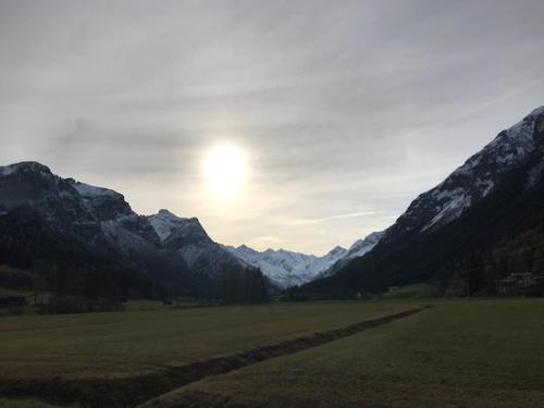 a field with mountains and the sun in the sky at Katja´s Ferienwohnung in Trins