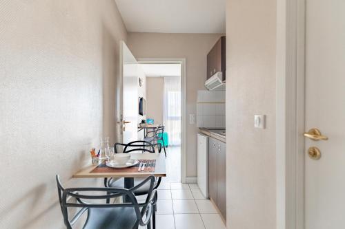 a kitchen and dining room with a table and chairs at Appart'City Classic Arlon - Porte du Luxembourg in Arlon