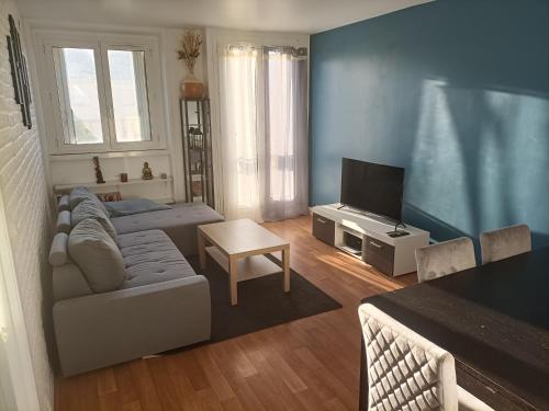 a living room with a couch and a television at Appartement cosy 6 personnes proche gare in Rueil-Malmaison