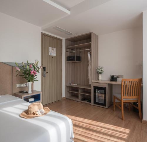 a bedroom with a bed and a desk with a hat on it at Le's Cham Hotel in Nha Trang