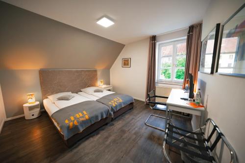 Schlafzimmer mit einem Bett, einem Schreibtisch und einem Fenster in der Unterkunft Hotel Bergbauer in Neuburg an der Donau
