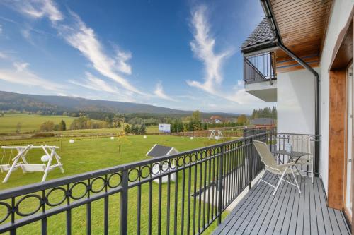 a balcony with chairs and a view of a field at Jagodowy Ski&Spa DeLux apartamenty z widokiem na góry,4km od Zieleniec Ski Arena Podgrzewany basen zewnętrzny latem,bilard,Wi-Fi w cenie Restauracja,balia,sauna na miejscu in Lasowka
