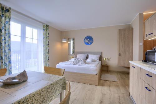 a bedroom with a bed and a kitchen with a table at Jagodowy Ski&Spa DeLux apartamenty z widokiem na góry,4km od Zieleniec Ski Arena Podgrzewany basen zewnętrzny latem,bilard,Wi-Fi w cenie Restauracja,balia,sauna na miejscu in Lasowka
