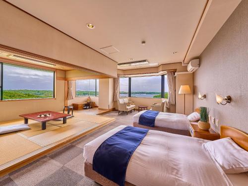 a hotel room with two beds and a table at Yukai Resort Premium Shima Saichoraku in Shima