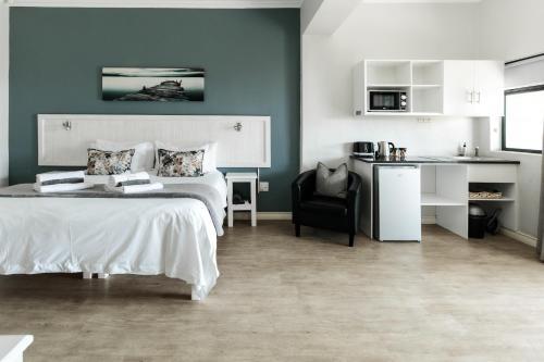 a bedroom with a bed and a chair and a kitchen at Bona Vista Self-Catering Accommodation in Klapmuts