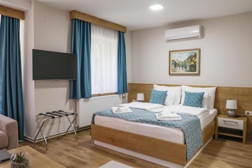 a bedroom with a bed with blue curtains and a tv at Grand Park rooms & apartments in Čačak