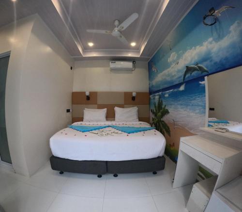 a bedroom with a bed and a painting on the wall at Wind Breeze Sunset View Inn in Guraidhoo