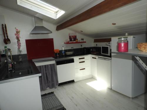 a kitchen with white cabinets and a red appliance at Appartement mansardé et climatisé 50 m2 in Pompignan
