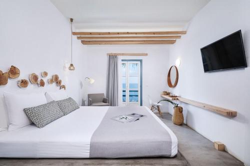 a white bedroom with a bed and a tv at Chrysalis Boutique - Adults Only in Astypalaia Town