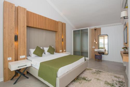 a bedroom with a large bed with a green blanket at BEACHFRONT WHITE VILLA WİTH PRIVATE SWIMMING POOL in Kalkan