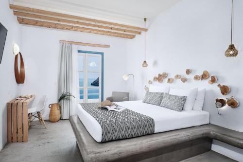 a white bedroom with a large bed and a table at Chrysalis Boutique - Adults Only in Astypalaia Town