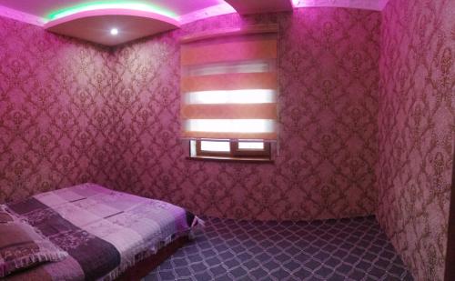 1 dormitorio con cama y ventana con iluminación púrpura en Дом у подножия гор en Chimgan