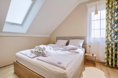 a bedroom with a bed with white sheets and a window at Jagodowy Ski&Spa DeLux apartamenty z widokiem na góry,4km od Zieleniec Ski Arena Podgrzewany basen zewnętrzny latem,bilard,Wi-Fi w cenie Restauracja,balia,sauna na miejscu in Lasowka