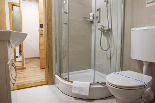 a bathroom with a shower with a toilet and a sink at Grand Park rooms & apartments in Čačak