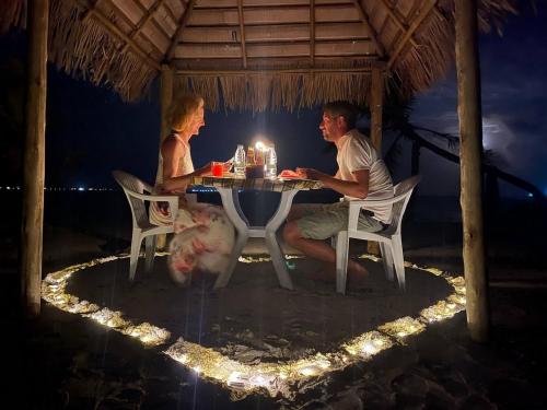 a man and woman sitting at a table with a candle at Wind Breeze Sunset View Inn in Guraidhoo