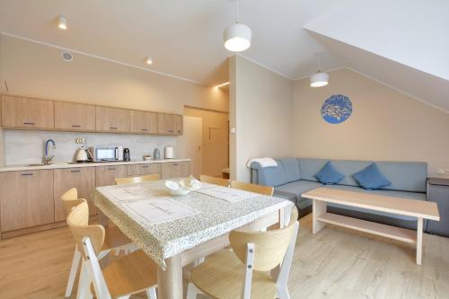 a kitchen and living room with a table and a couch at Jagodowy Ski&Spa DeLux apartamenty z widokiem na góry,4km od Zieleniec Ski Arena Podgrzewany basen zewnętrzny latem,bilard,Wi-Fi w cenie Restauracja,balia,sauna na miejscu in Lasowka