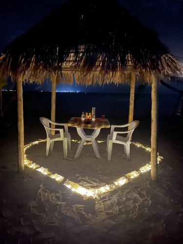 a table and chairs on the beach at night at Wind Breeze Sunset View Inn in Guraidhoo
