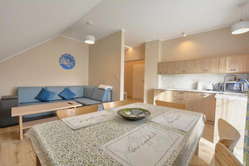 a kitchen and a living room with a table and a couch at Jagodowy Ski&Spa DeLux apartamenty z widokiem na góry,4km od Zieleniec Ski Arena Podgrzewany basen zewnętrzny latem,bilard,Wi-Fi w cenie Restauracja,balia,sauna na miejscu in Lasowka