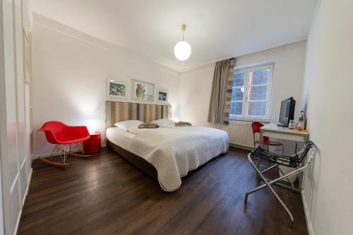 a bedroom with a bed and a red chair at Hotel Bergbauer mit Late-Self-Check-IN in Neuburg an der Donau