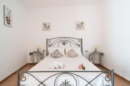 um quarto com uma cama com lençóis brancos e almofadas em La casa del sole em Loculi