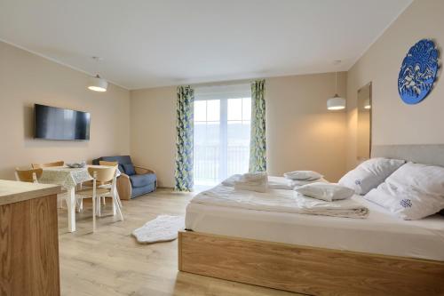 a bedroom with a large bed and a living room at Jagodowy Ski&Spa DeLux apartamenty z widokiem na góry,4km od Zieleniec Ski Arena Podgrzewany basen zewnętrzny latem,bilard,Wi-Fi w cenie Restauracja,balia,sauna na miejscu in Lasowka