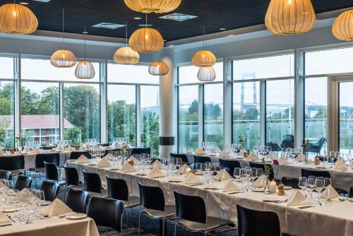 a banquet hall with tables and chairs and windows at Comwell Middelfart in Middelfart