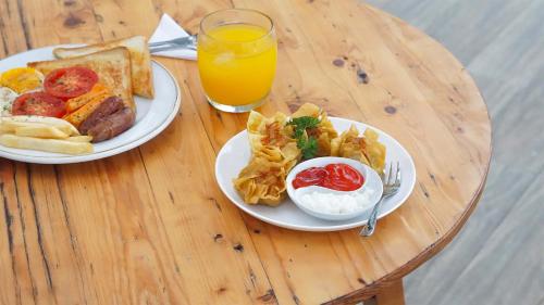 a table with two plates of food and a glass of orange juice at My Dormy Hostel UMM in Malang